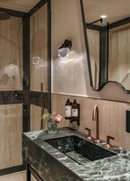 A modern bathroom with a marble sink, copper fixtures, and a wall-mounted mirror.