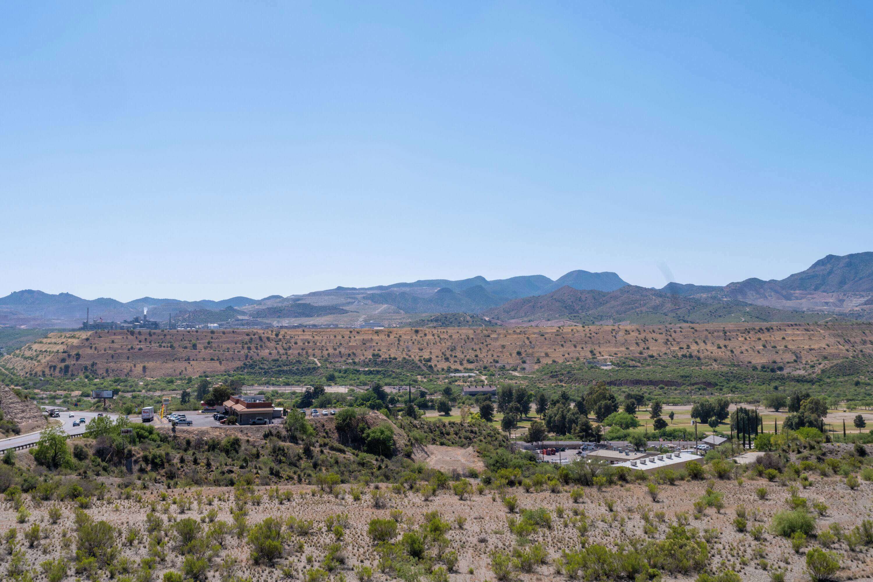 Paisaje rural con un pueblo pequeño, algunos edificios y montañas al fondo.
