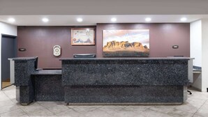 A reception desk with a marble top, a framed picture of a landscape, and a clock on the wall.