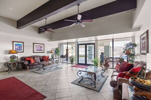 Uma sala de estar espaçosa com pé direito alto, ventiladores de teto, uma janela grande e vista para o exterior.