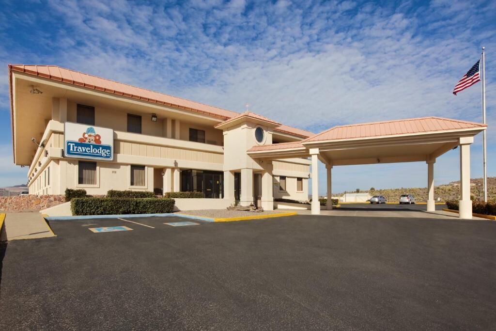 A Travelodge hotel with a covered parking area and a clear sky.