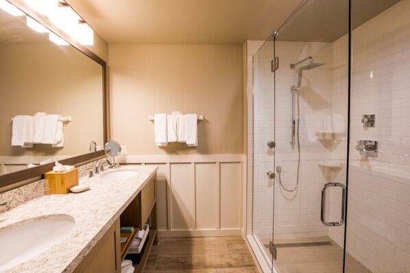 Un baño moderno con ducha de vidrio, tocador doble y un espejo grande.