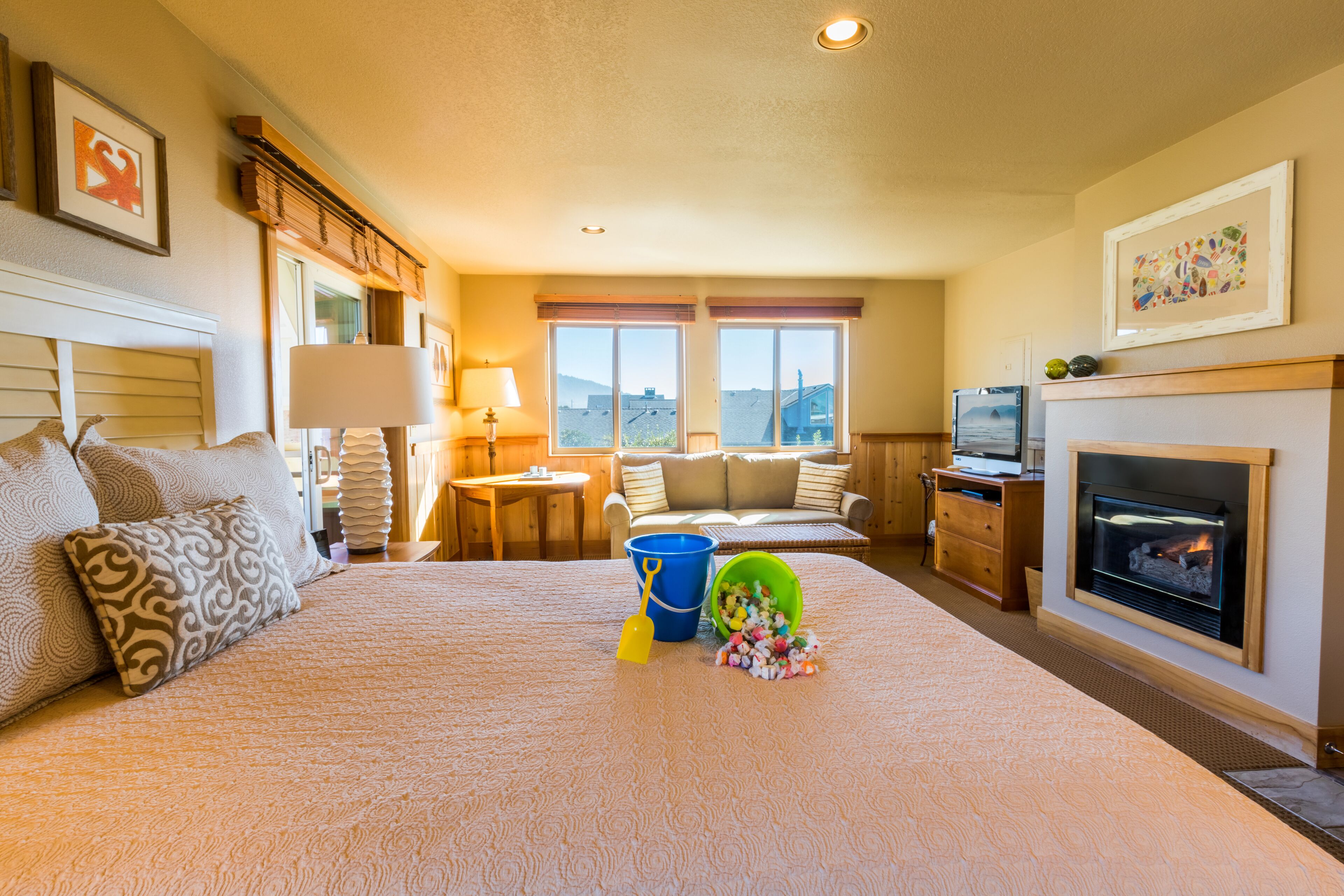 A hotel room with a large bed, a fireplace, a television, and a view of the mountains through the windows.