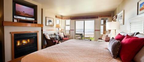 Habitación de hotel con una cama grande, chimenea, televisión y balcón con vistas.