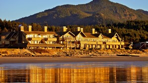 A beachfront hotel with multiple buildings, including a prominent structure with a stone chimney and a balcony. - The Ocean Lodge (Cannon Beach)