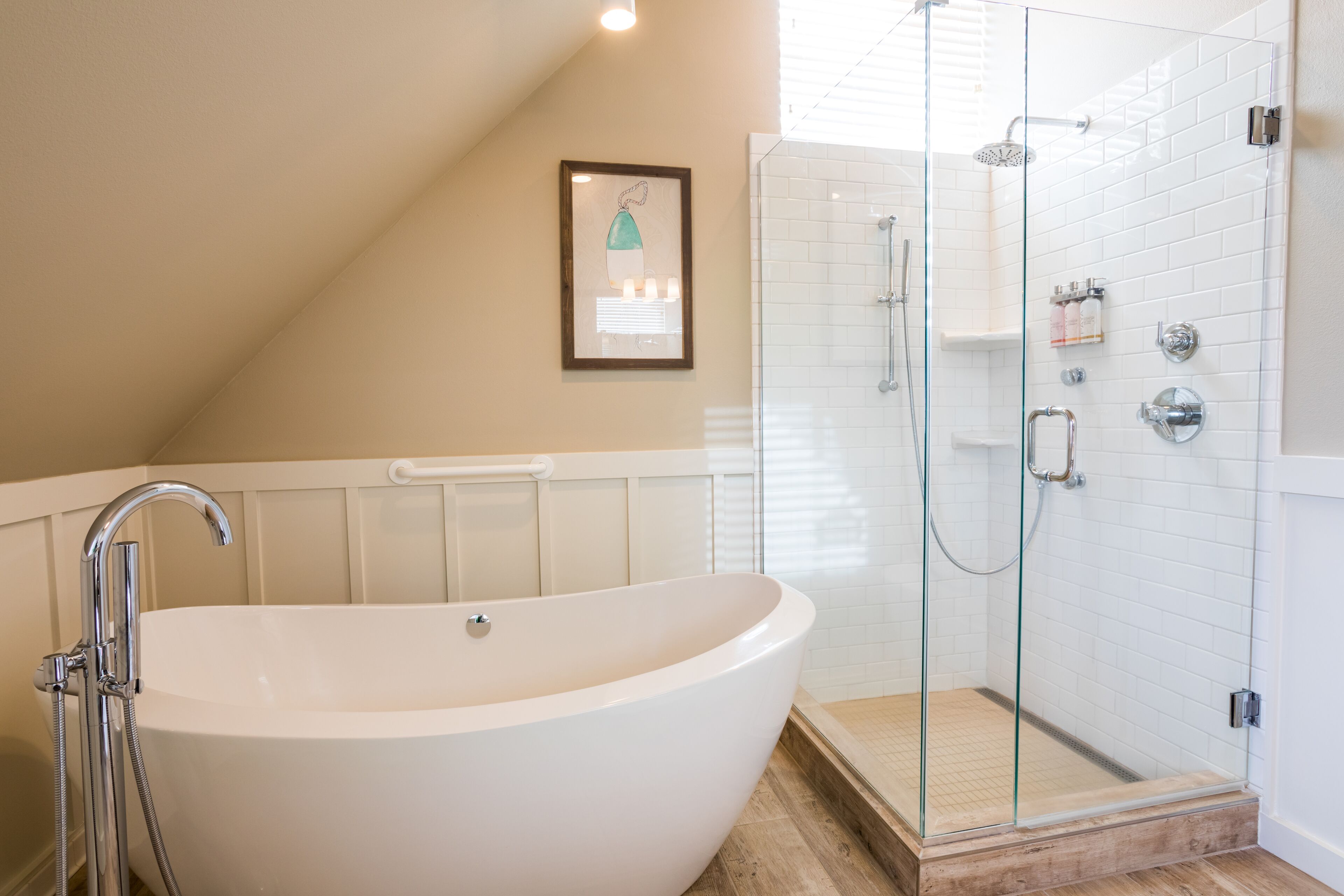 Ein modernes Badezimmer mit einer freistehenden Badewanne, einer gläsernen Dusche und einem gerahmten Kunstwerk an der Wand.