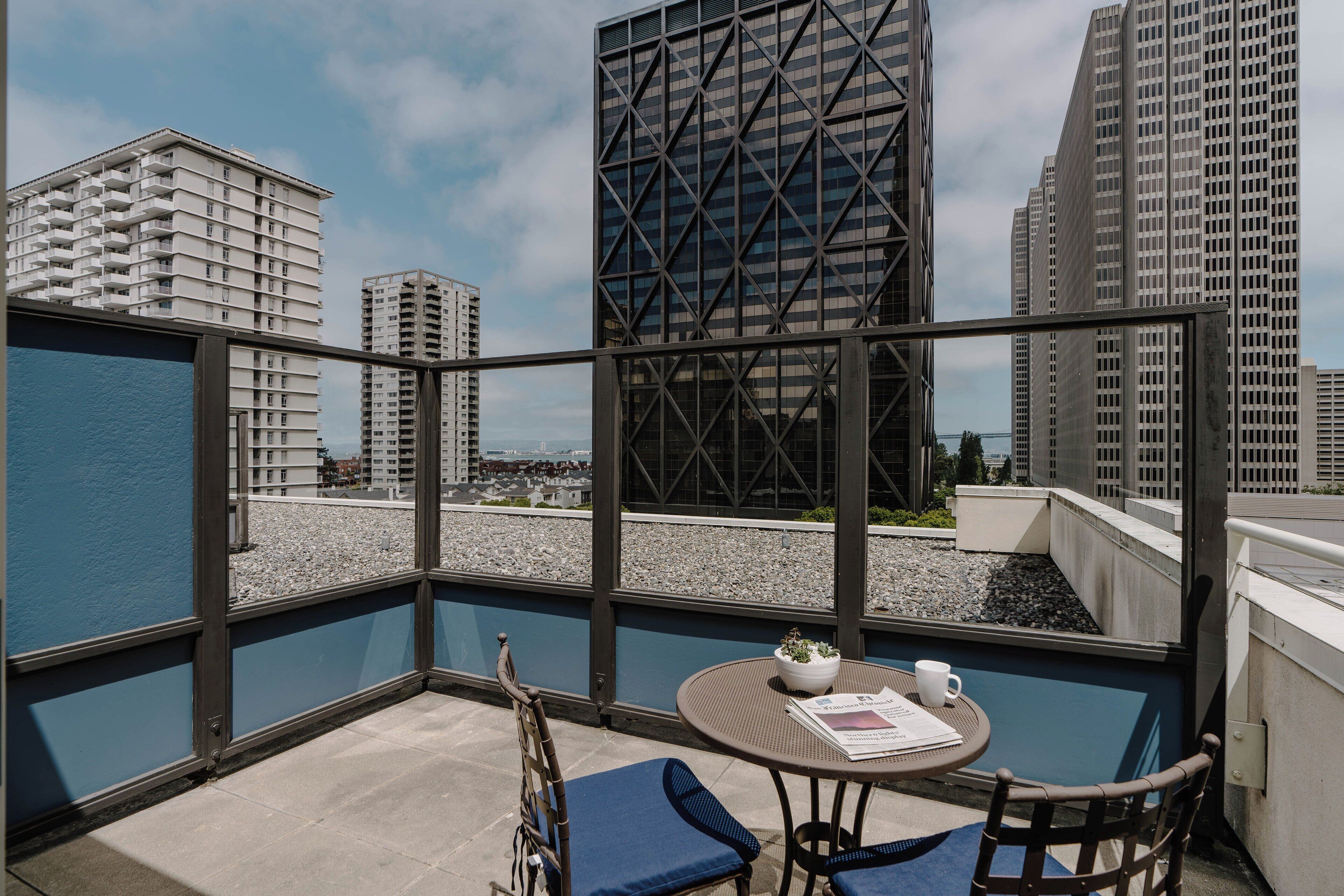 A balcony with a table, chairs, and a view of city buildings.