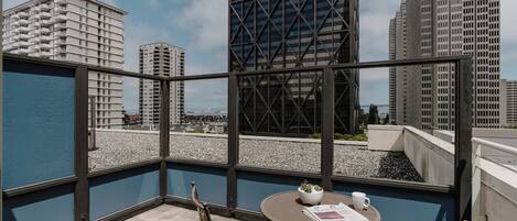 A balcony with a table, chairs, and a view of city buildings.