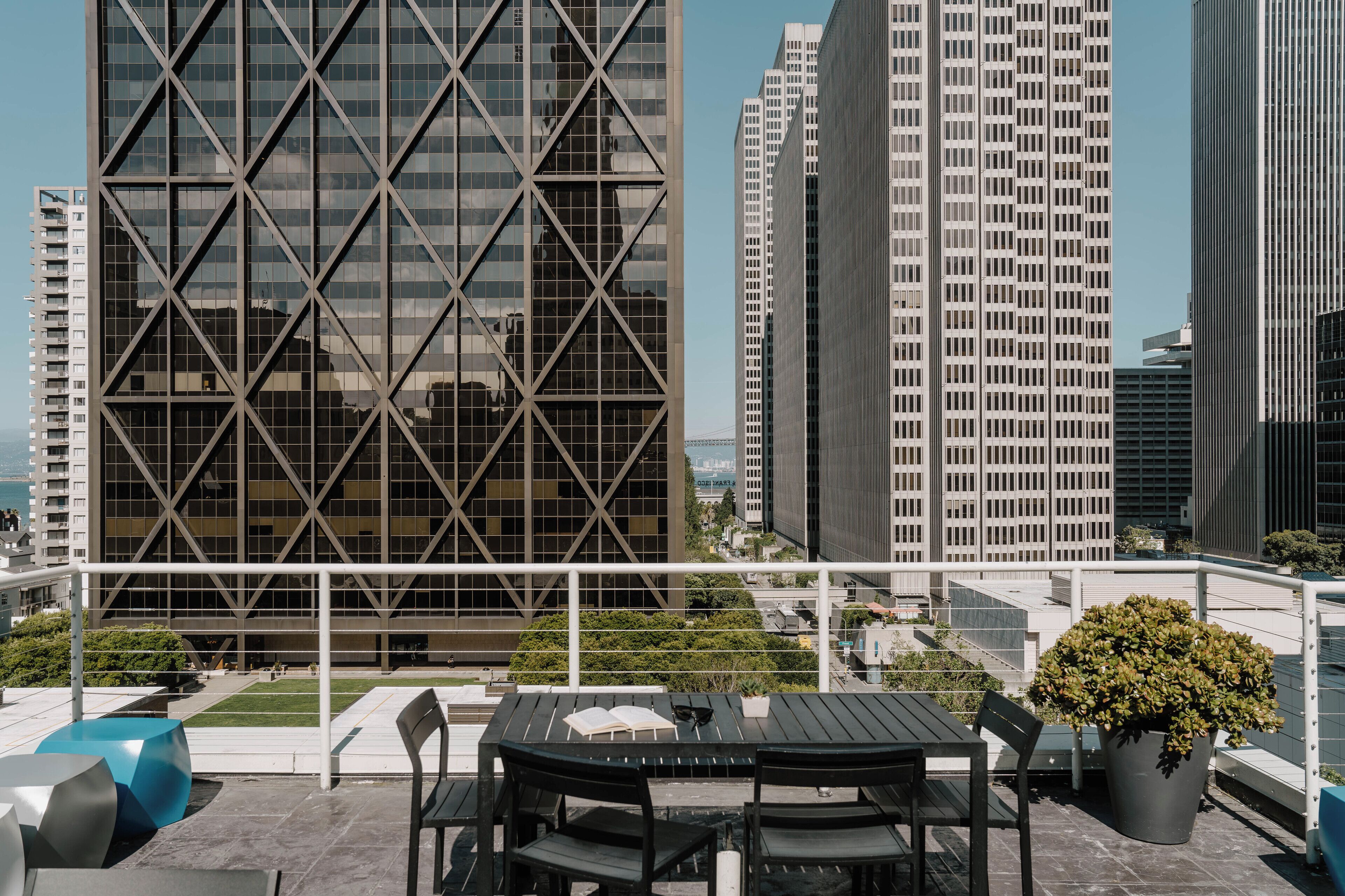 A rooftop terrace with outdoor seating and a view of modern buildings.