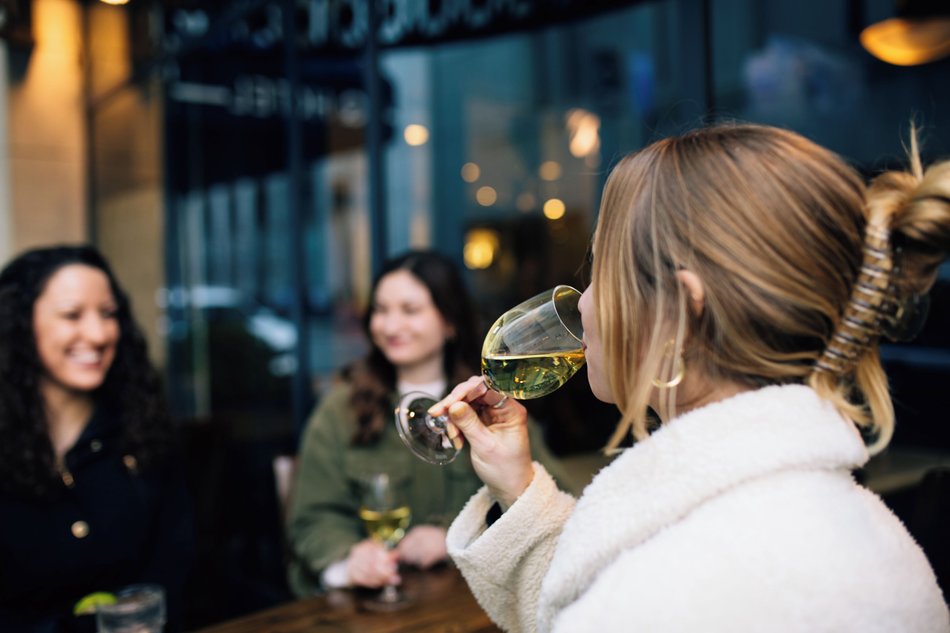 A group of people sitting at a table in a restaurant, with one person holding a wine glass.