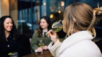 A group of people sitting at a table in a restaurant, with one person holding a wine glass.
