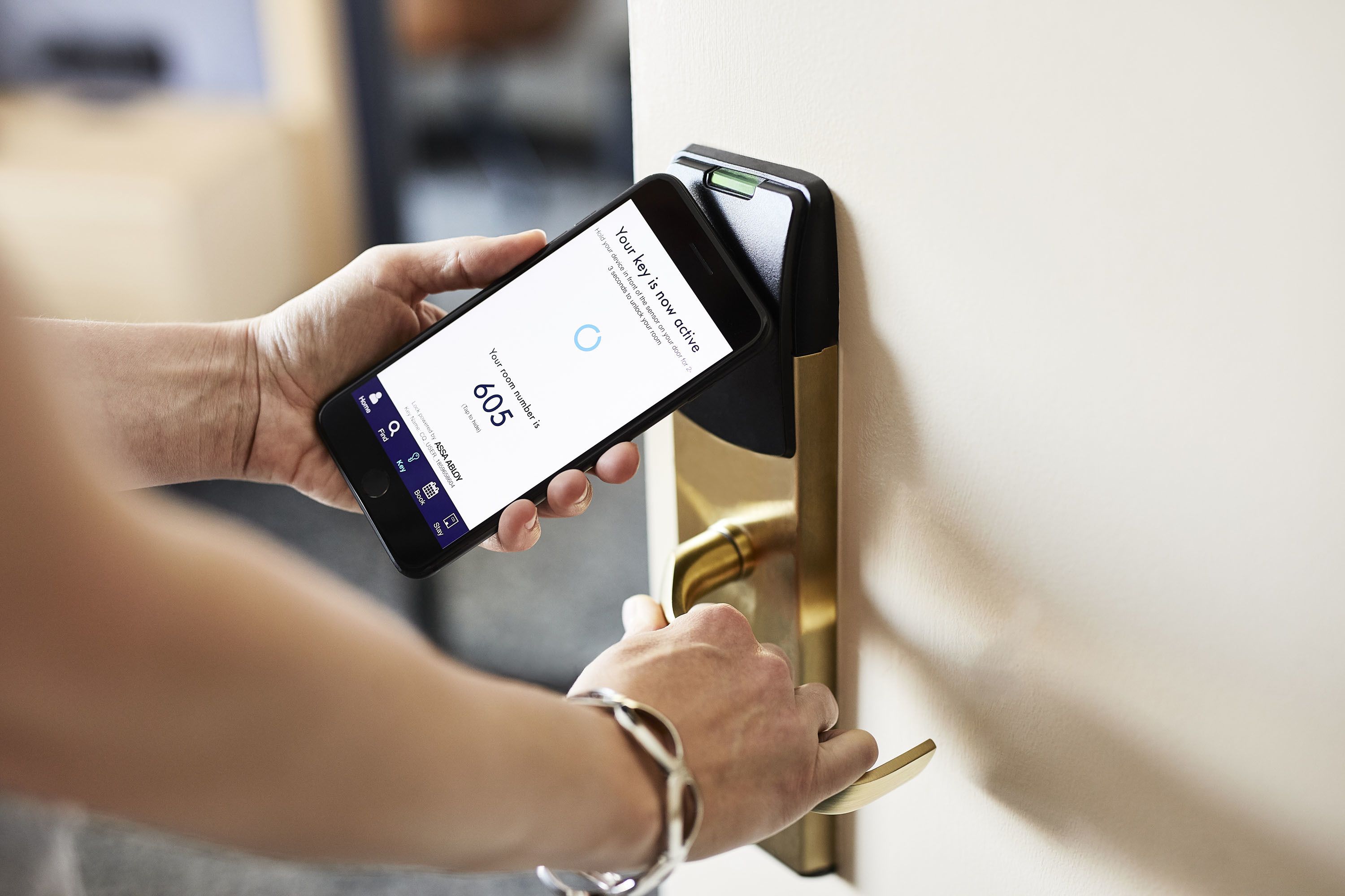A person using a smartphone to interact with a digital lock on a door.