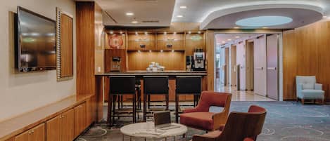 A lobby with a bar area, seating, a TV, and a patterned carpet.