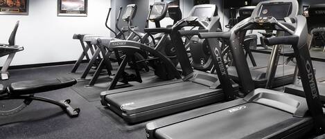 A gym with treadmills, ellipticals, and a bench.