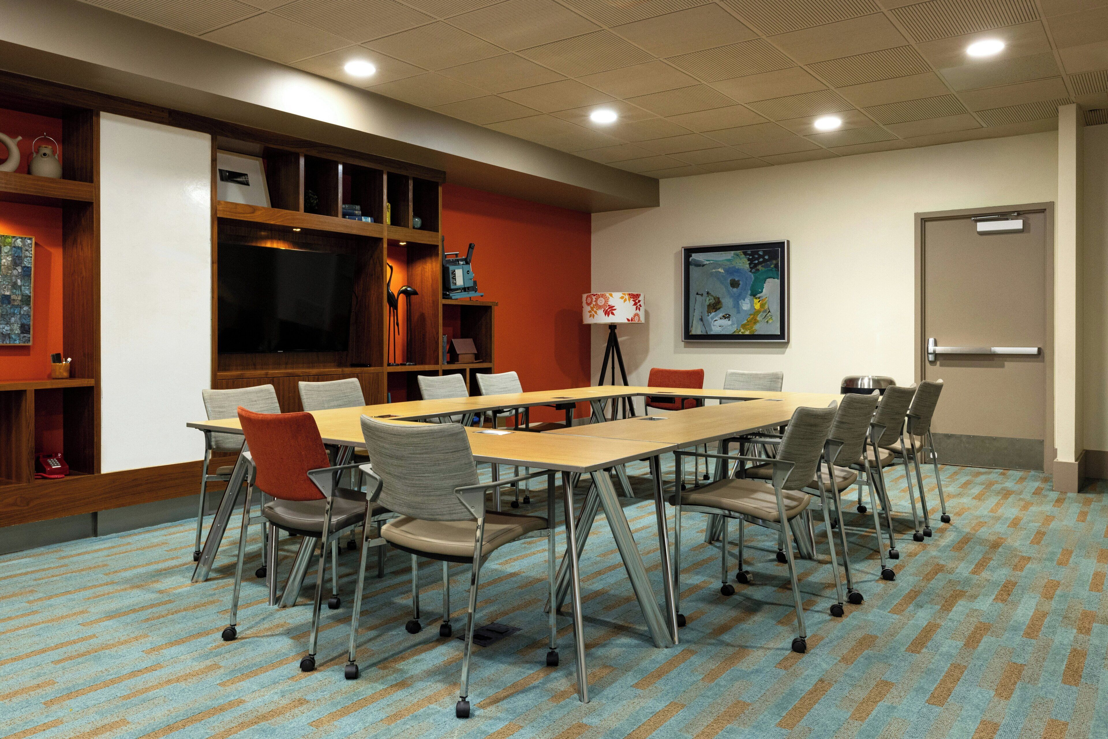 A conference room with a long table, chairs, a projector, and a whiteboard.
