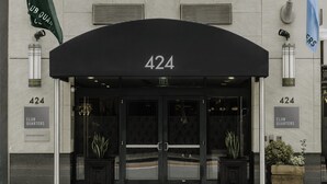 A building entrance with a black awning displaying the number 424. There are two flags on either side of the entrance, one green and one blue. - Club Quarters Hotel Embarcadero, San Francisco (San Francisco)