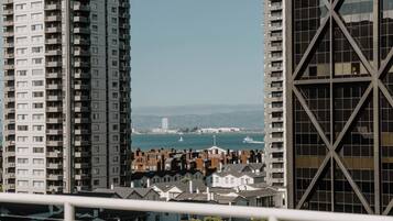 Un edificio alto con varios balcones, vista al mar y un paisaje urbano distante.