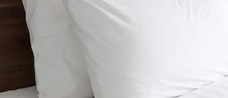 A bed with white bedding and a striped pillow.