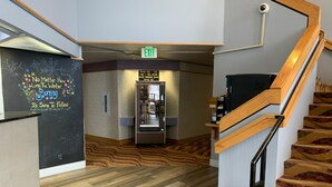 A hotel lobby with a wooden staircase, an exit sign, vending machines, and a motivational quote on the wall. - Red Lion Inn & Suites Post Falls (Post Falls)