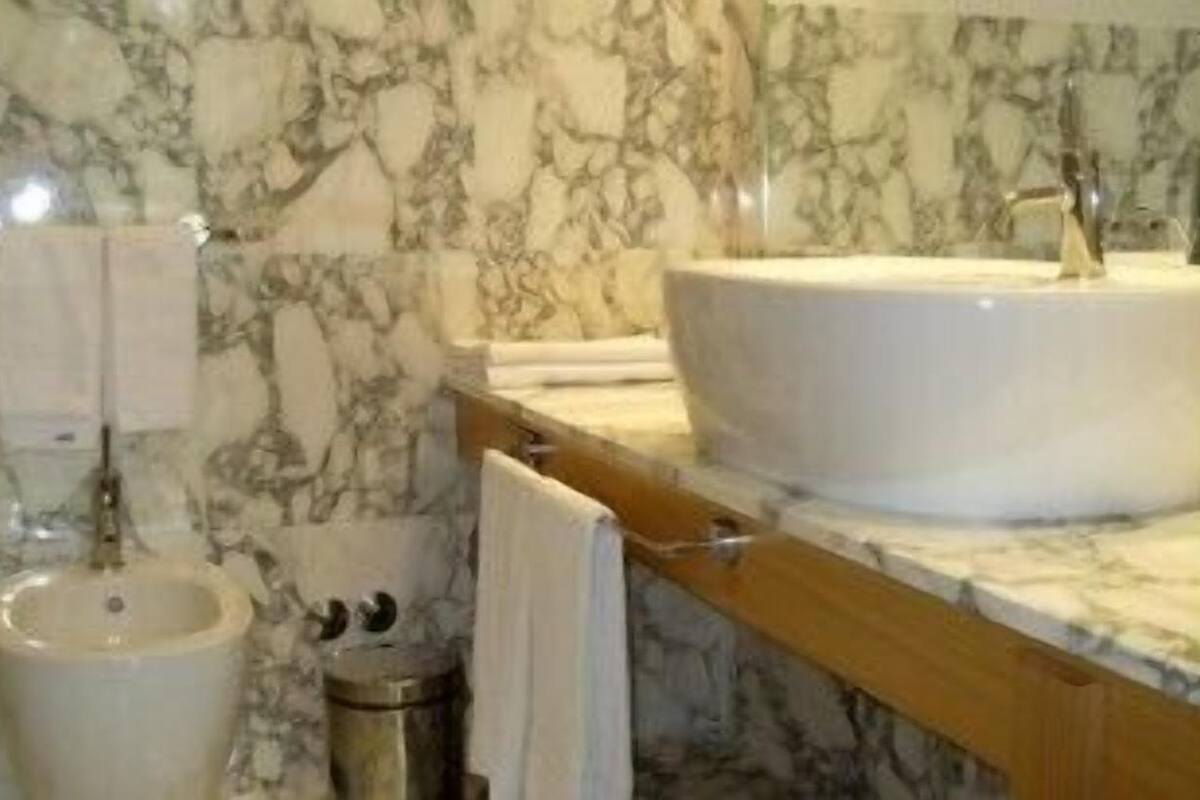 A bathroom with a marble sink, a mirror, and a towel rack.