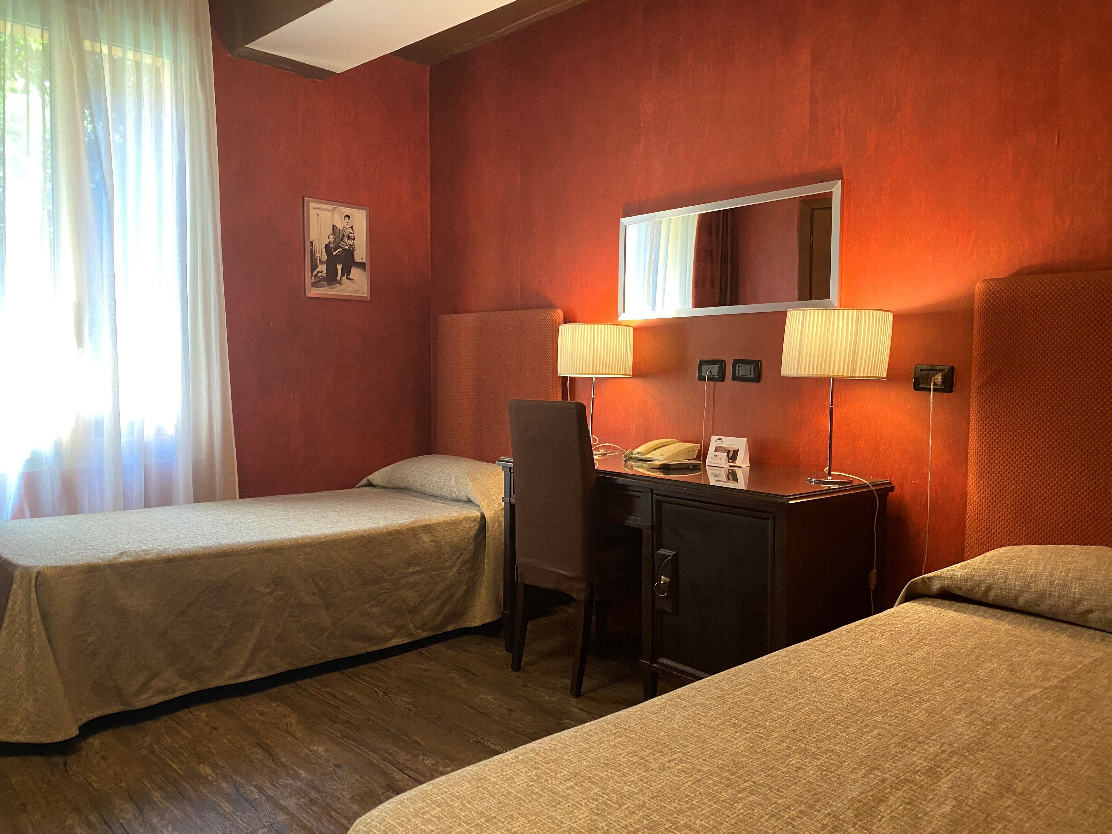 Ein Hotelzimmer mit zwei Einzelbetten, einem Schreibtisch mit Telefon und zwei Wandlampen.