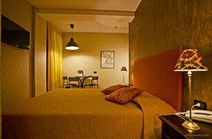 Una habitación de hotel con cama, un escritorio con sillas, una lámpara y un teléfono.
