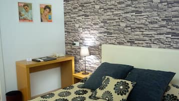Un dormitorio con cama, mesita de noche, lámpara y pared con diseño de piedra.