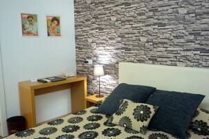 Un dormitorio con cama, mesita de noche, lámpara y pared con diseño de piedra.