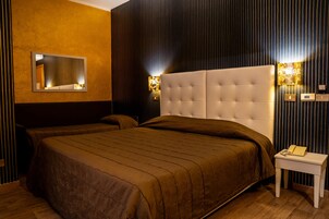 Habitación de hotel con una cama grande, una mesita de noche con teléfono y dos lámparas de pared.