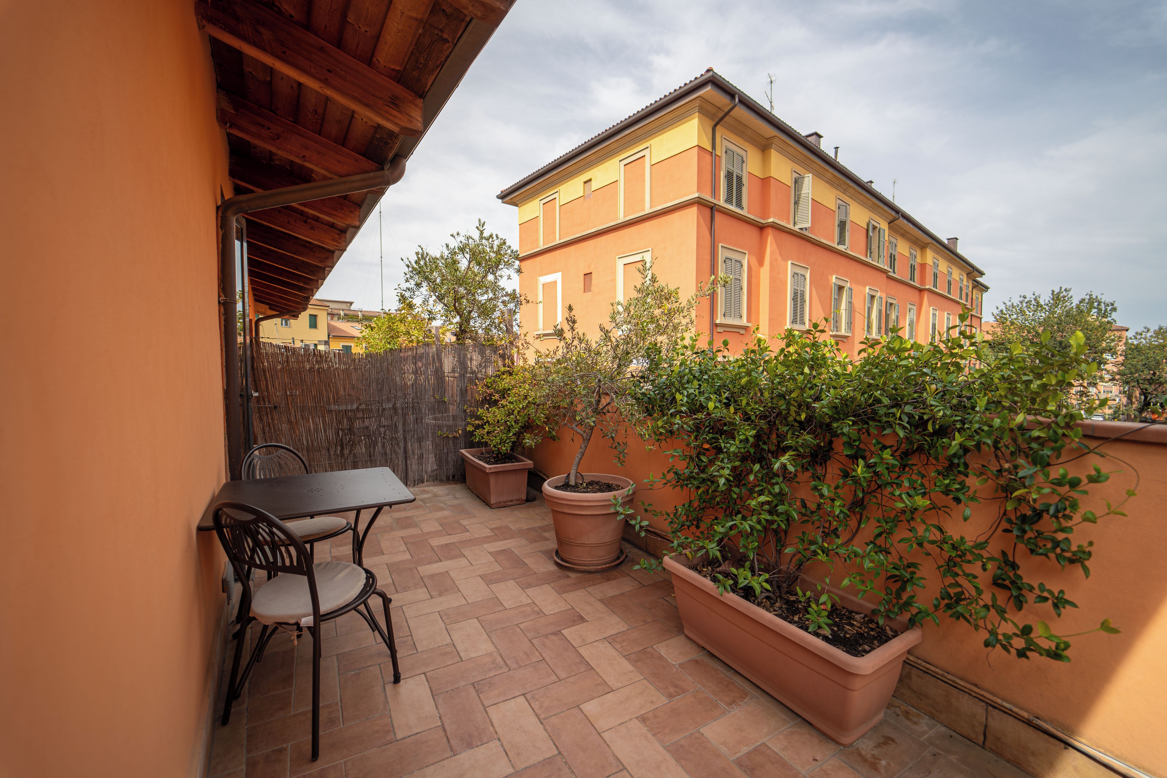 A patio with a table and chairs, surrounded by potted plants and a wooden fence.