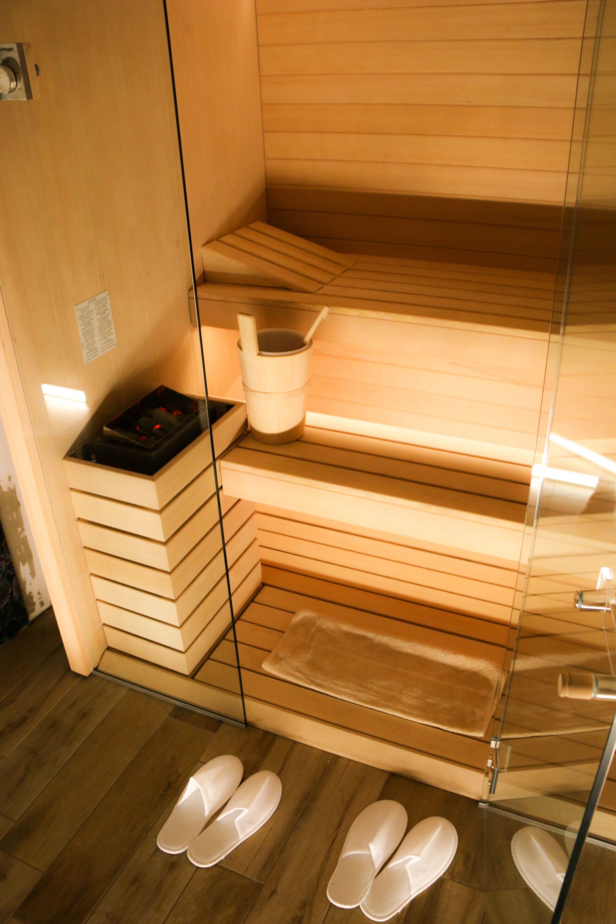 Una sauna con panche in legno, un tavolino e un catino.