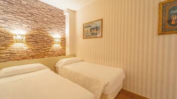 A hotel room with two beds, a stone accent wall, and a painting on the wall.
