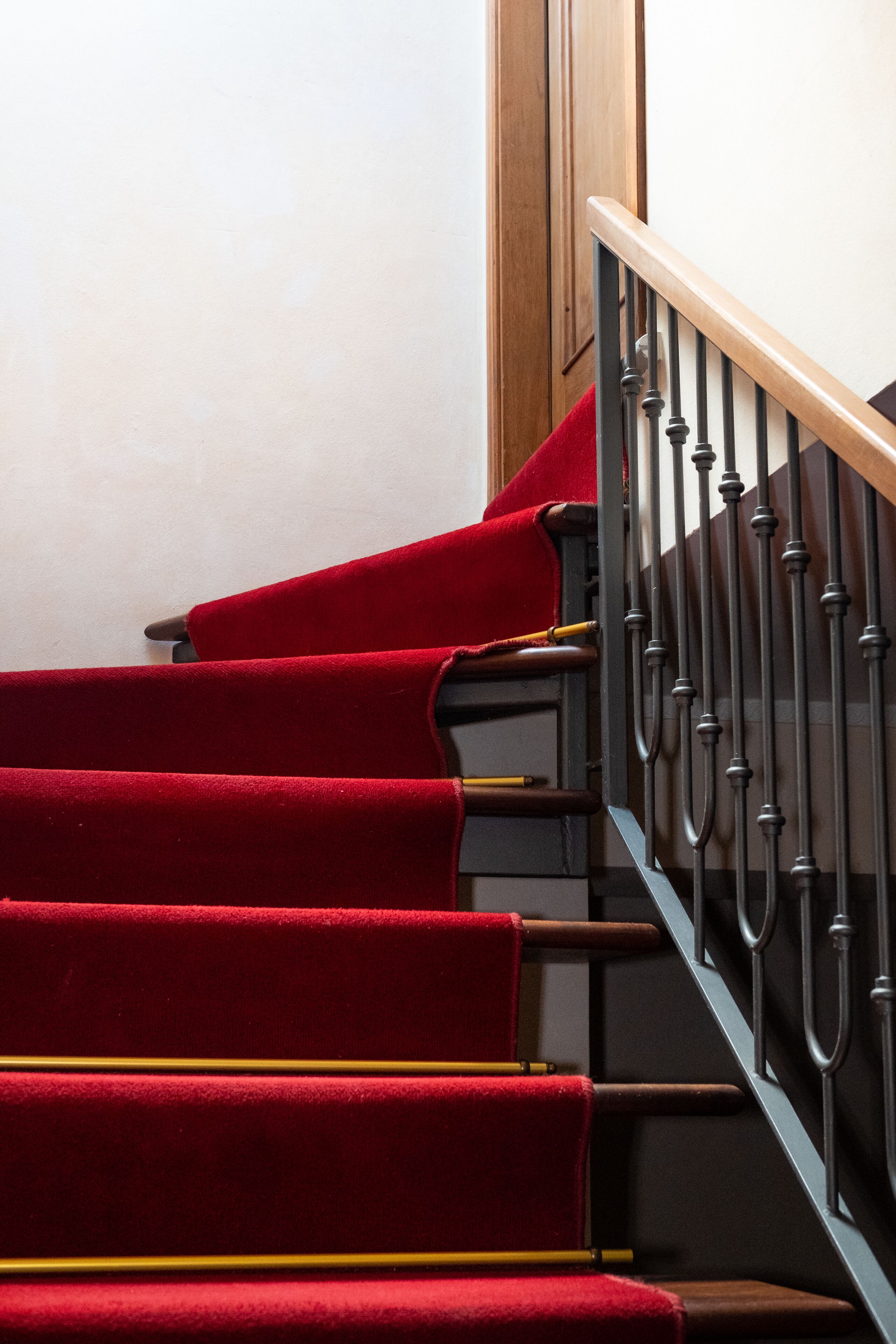 A staircase with red carpeted steps and a wooden handrail.