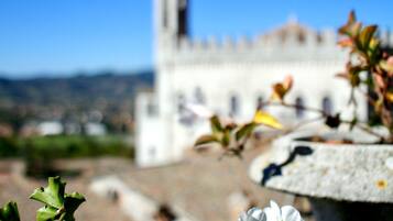 Une vue d’un bâtiment historique doté d’une tour, entouré de verdure et de fleurs.