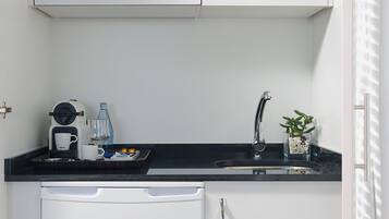 Una cocina pequeña con microondas, cafetera y lavabo.