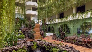 A multi-level atrium with a central water feature, surrounded by lush greenery and modern architecture. - H10 Taburiente Playa (Brena Baja)