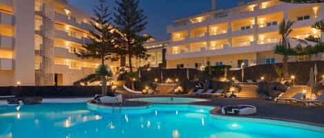 Un resort con piscina, varios balcones y zonas de estar al aire libre.