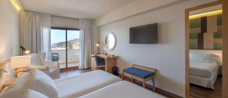 A hotel room with two beds, a desk, a chair, a TV, and a large mirror.