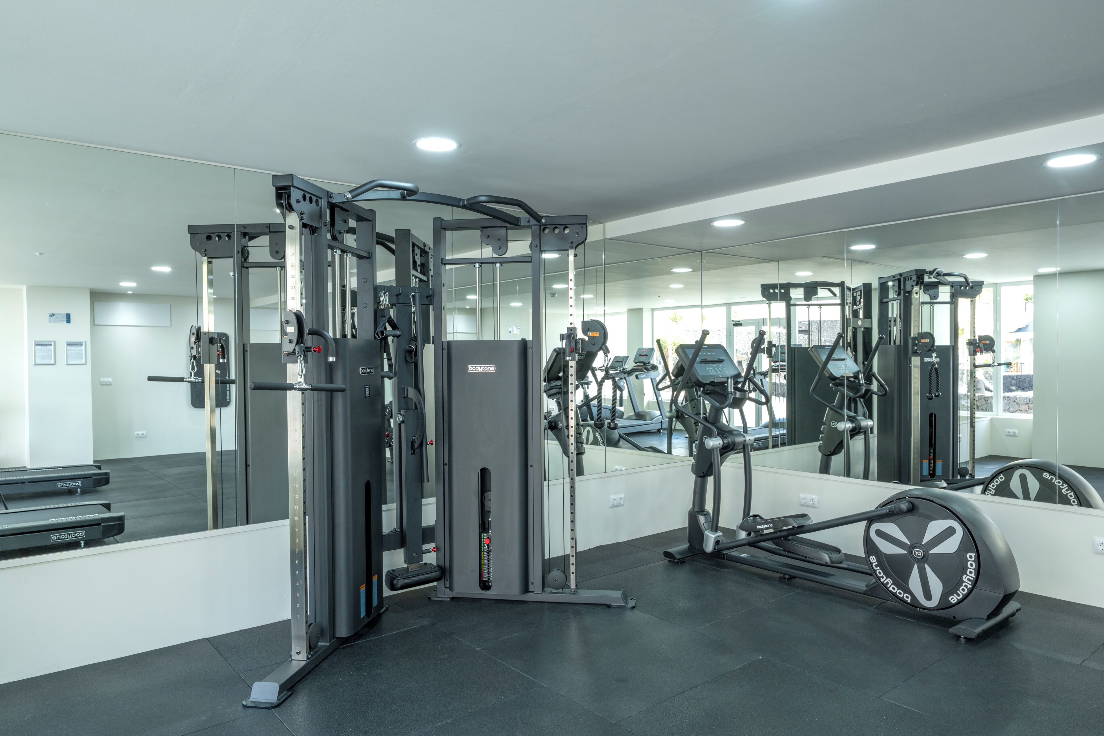 A gym with exercise equipment, a mirrored wall, and a treadmill.