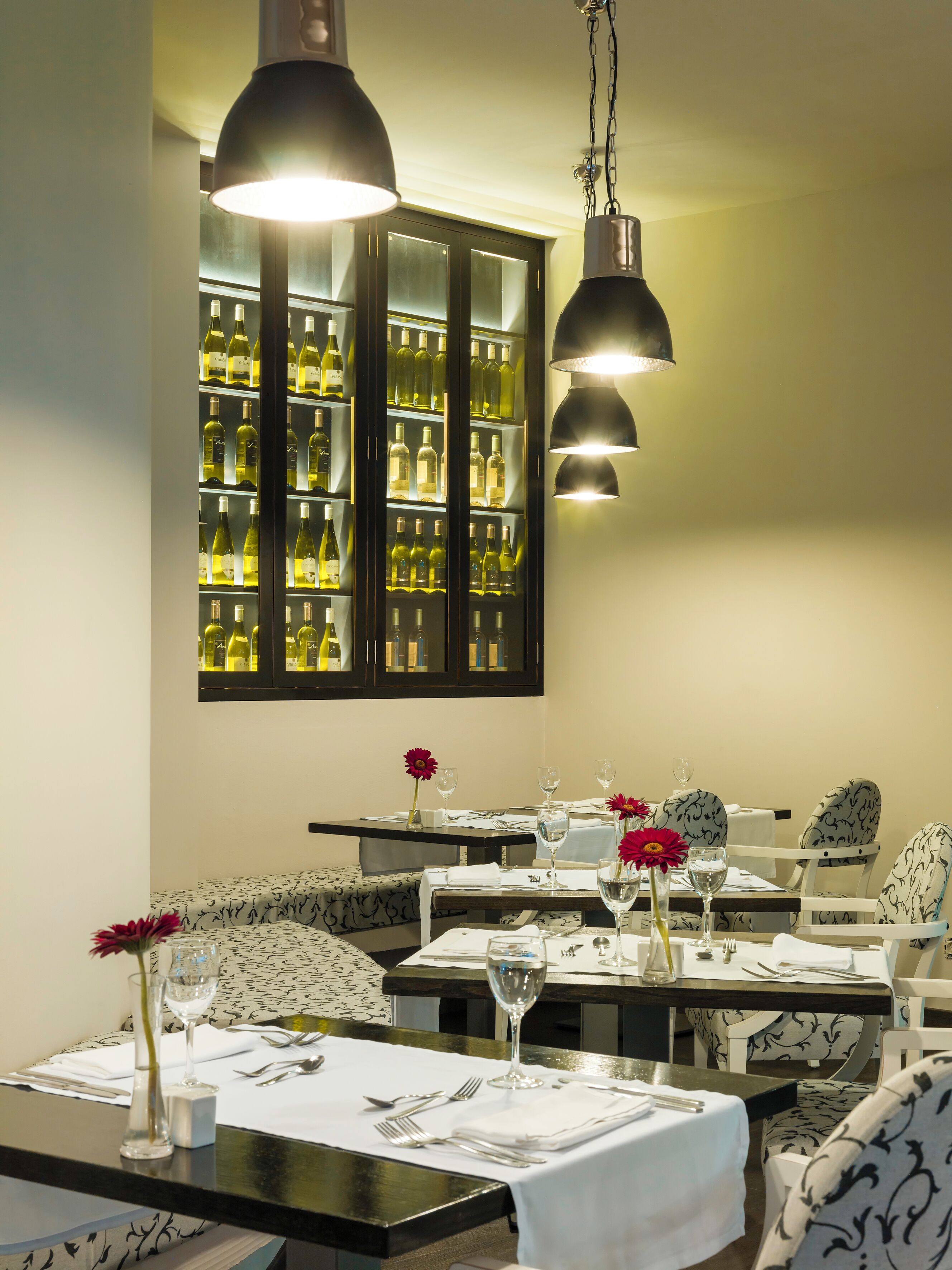 A restaurant interior with a wine cellar, dining tables, and chairs.