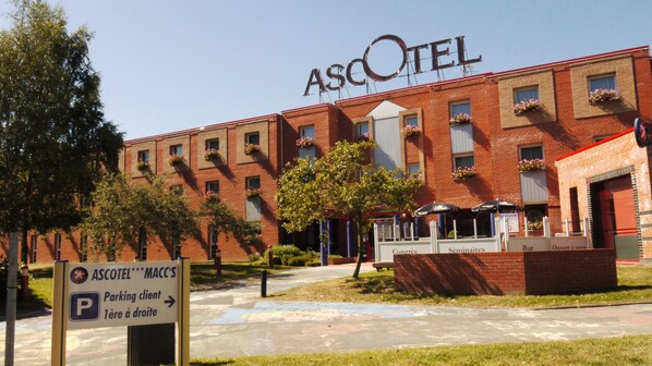 Experience the charm of Ascotel, where a brick facade and lush greenery meet at the entrance.