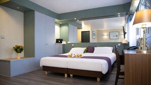 Une chambre d’hôtel moderne avec un grand lit, des tables de chevet, un bureau et un miroir.