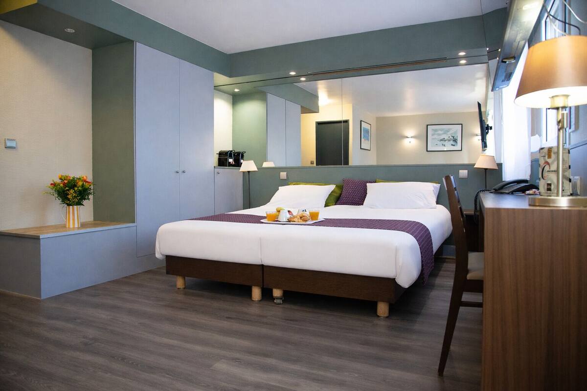 Een moderne hotelkamer met een groot bed, nachtkastjes, een bureau en een spiegel.