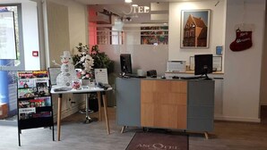 Un comptoir d’accueil avec un ordinateur, une plante et un présentoir à magazines.