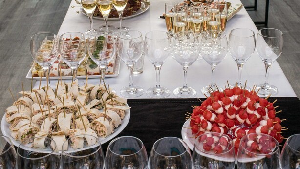 Une longue table dressée pour un événement formel, avec une variété de plats et de boissons proposés.