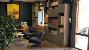Une pièce avec une bibliothèque, un bureau, une chaise et une grande fenêtre.