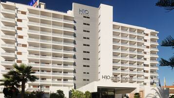 Un hotel de varios pisos con diseño moderno, que cuenta con balcones en cada planta y una entrada destacada.