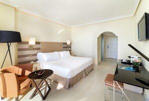 Une chambre d’hôtel avec un lit, un bureau, une chaise, une lampe et un téléviseur.