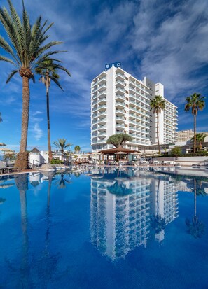 A hotel with a pool, palm trees, and a clear blue sky. - H10 Gran Tinerfe (Adeje)