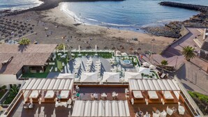 Un bar en la azotea con asientos al aire libre, piscina y vistas a la playa y al océano.